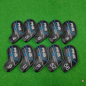 Puede incluir: Un conjunto de diez fundas negras para palos de golf con la marca "PING" y "G440" impresas. Cada funda tiene un número o letra diferente. Las fundas están dispuestas sobre una superficie verde.