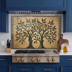 May include: A mosaic backsplash featuring two stylized trees with birds perched in the branches. The mosaic is made of small, square tiles in shades of gold, brown, green, and blue. The backsplash is installed above a stainless steel gas range.