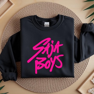 May include: Black crewneck sweatshirt with the text "Stija Boys" in bright pink, a casual and stylish design. The sweatshirt is made of a soft material and is suitable for everyday wear.