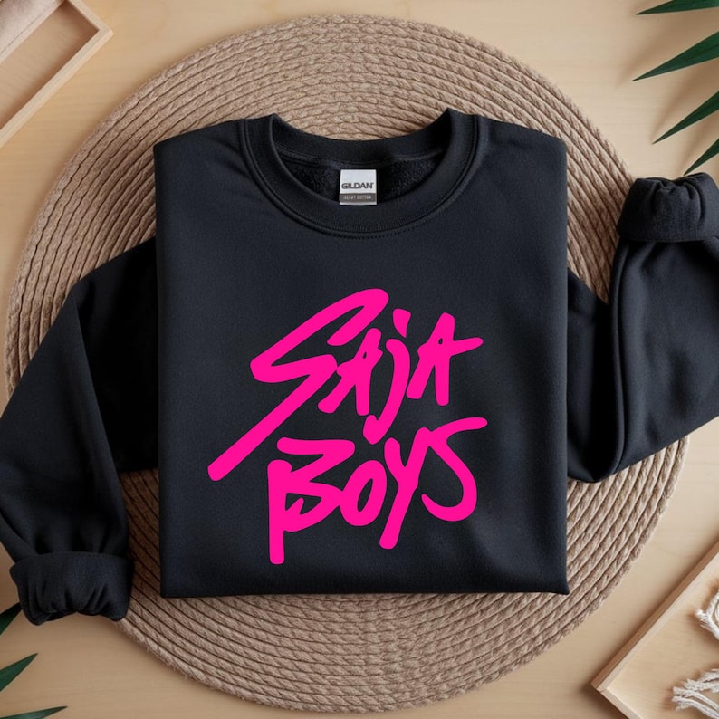 May include: Black crewneck sweatshirt with the text "Stija Boys" in bright pink, a casual and stylish design. The sweatshirt is made of a soft material and is suitable for everyday wear.