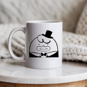May include: White ceramic mug featuring a cartoon character in a tuxedo and top hat. The black and white illustration depicts a round-faced figure with a bow tie and a stern expression. The mug has a curved handle.