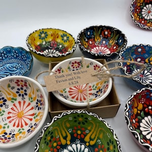 May include: A collection of colorful ceramic bowls with intricate floral patterns. The bowls feature a variety of colors, including yellow, blue, green, and red. One bowl has a tag that reads "Thank you! With love Favion and Lily 6.8.24".