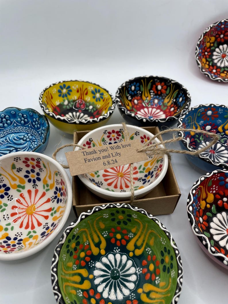May include: A collection of colorful ceramic bowls with intricate floral patterns. The bowls feature a variety of colors, including yellow, blue, green, and red. One bowl has a tag that reads "Thank you! With love Favion and Lily 6.8.24".