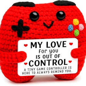 May include: A red crocheted plush toy shaped like a game controller with black eyes, a black directional pad, and colorful buttons. It holds a white rectangular sign that reads: MY LOVE For you IS OUT OF CONTROL. A TINY GAME CONTROLLER IS HERE TO ALWAYS REMIND YOU.