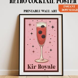 May include: A framed retro cocktail poster with the text "Retro Cocktail Poster" and "Printable Wall Art". The image features a Kir Royale cocktail in a champagne flute with blackberries, set against a pink background. The words "Instant Download" are also present.
