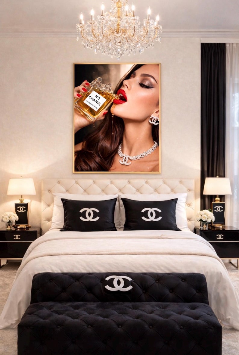 Puede incluir: Un dormitorio lujoso con una obra de arte enmarcada de una mujer bebiendo perfume. La cama tiene almohadas negras y un banco, todos adornados con el logo de Chanel. Mesitas de noche negras con l&aacute;mparas y una ara&ntilde;a completan la opulenta decoraci&oacute;n.