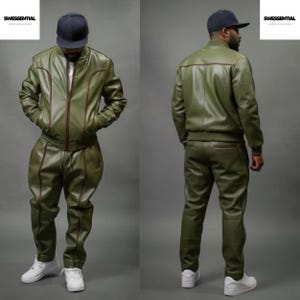 May include: Olive green leather tracksuit with brown trim. The jacket has a zip closure and the pants have a relaxed fit. The outfit is paired with white sneakers. The brand name "SWESSENTIAL" is visible in the top left and right corners.