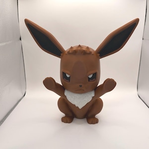 May include: A brown figurine of a cartoon character with large ears, a white collar, and an angry expression. The figure has its arms outstretched and is in a sitting position. The ears are brown with black inner ears.