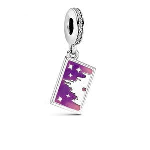 May include: A silver charm with a rectangular pendant featuring a purple and pink gradient design. The pendant has a white silhouette of a castle and stars. The charm's top ring is adorned with small, clear stones.