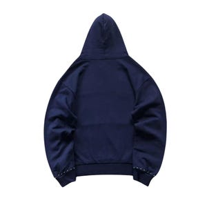 May include: Navy blue hoodie with a drawstring hood. The back view shows a clean design with small silver studs along the cuffs. A casual and comfortable garment for everyday wear.