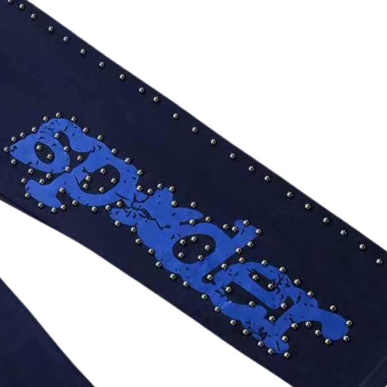 May include: Dark blue denim pants with a blue graphic design and silver studs. The word "Spider" is spelled out in a distressed blue font and is surrounded by small silver studs. The pants are a solid dark blue color.