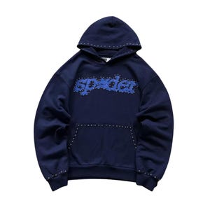 May include: Navy blue hoodie with the word "spyder" in blue, studded with silver rivets. The hoodie has a drawstring hood and a front pocket. The cuffs and hood are also studded with silver rivets. A casual, comfortable garment.
