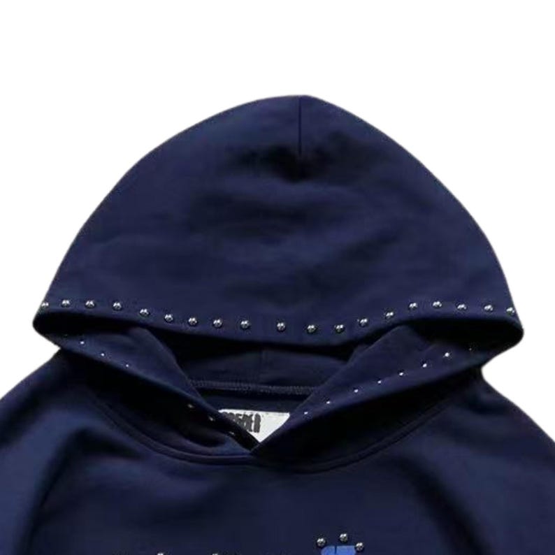 May include: Navy blue hoodie with a studded hood trim. The hood is lined with a matching fabric. The hoodie has a drawstring and a front pocket. The overall design is simple and modern.
