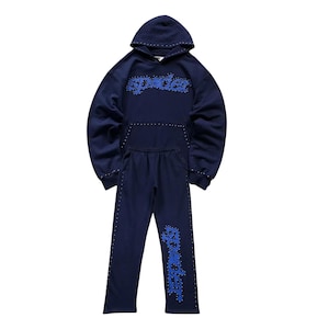 May include: A navy blue hoodie and sweatpants set. The hoodie features the word "spider" in blue, stylized text across the chest, and the sweatpants have the same text on the left leg. Both pieces are adorned with small silver studs.