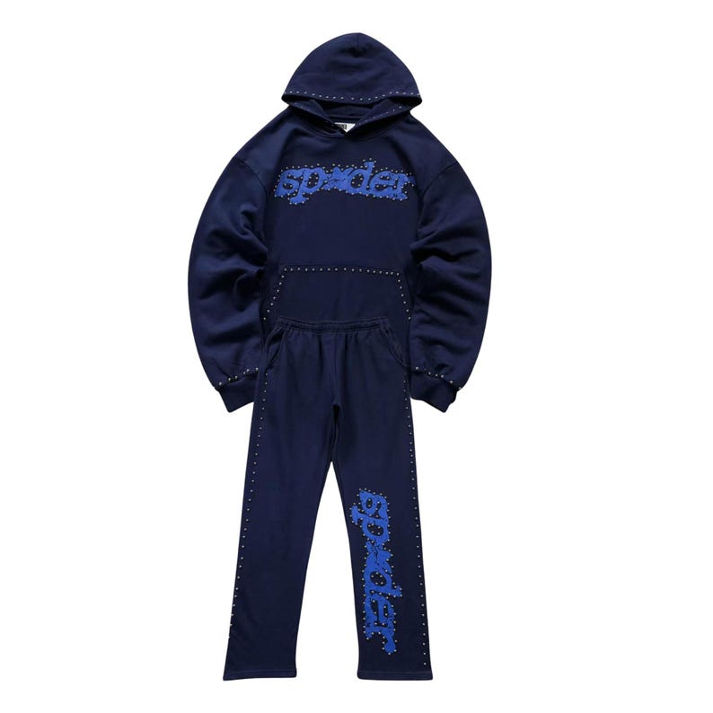 May include: A navy blue hoodie and sweatpants set. The hoodie features the word "spider" in blue, stylized text across the chest, and the sweatpants have the same text on the left leg. Both pieces are adorned with small silver studs.