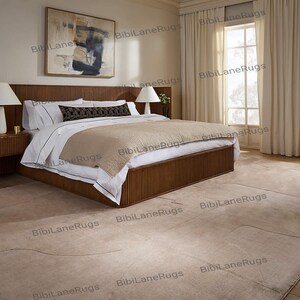 May include: A bedroom featuring a large wooden bed with a ribbed headboard and frame. The bed is made with white linens, a beige blanket, and decorative pillows. A beige rug covers the floor. Two bedside tables with lamps flank the bed. A large painting hangs on the wall.