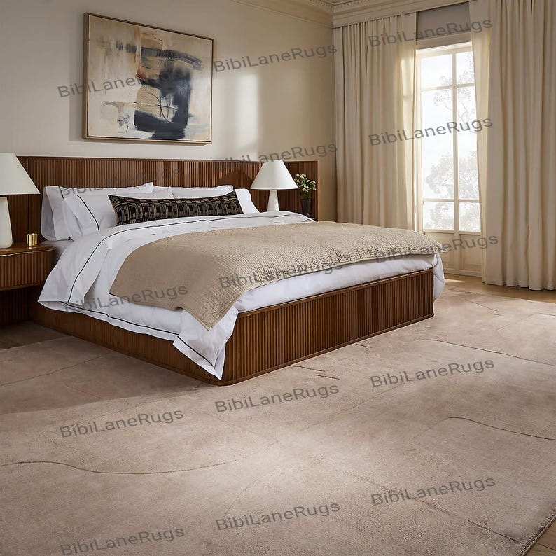 May include: A bedroom featuring a large wooden bed with a ribbed headboard and frame. The bed is made with white linens, a beige blanket, and decorative pillows. A beige rug covers the floor. Two bedside tables with lamps flank the bed. A large painting hangs on the wall.