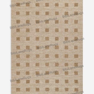 以下が含まれることがあります： ベージュ色の長方形ラグ。濃いベージュ色の正方形と長方形の繰り返し模様があります。ラグはテクスチャ加工されており、「BibiLane Rugs」の文字がプリントされています。