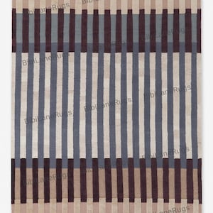 May include: A rectangular rug featuring a striped pattern in blue, brown, and beige. Vertical stripes alternate in colour, creating a geometric design. The rug has the text "BibiLaneRugs" repeated across the image.