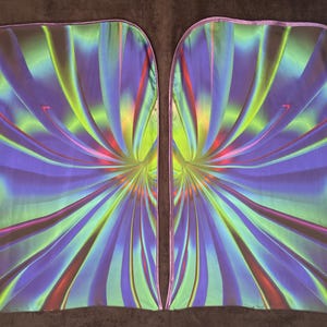 May include: Two rectangular, flowing fabric panels with a vibrant, abstract design. The pattern features radiating lines in shades of blue, green, purple, and pink. The edges are finished with a light purple trim. The overall effect is a colorful, dynamic textile.