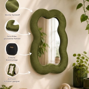 May include: An olive green, wavy-shaped wall mirror featuring a soft, plush velvet-covered frame. The design includes a thick, padded border and a rear mounting bracket for wall installation, along with a stand for tabletop display options.