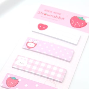 May include: Pink sticky notes with strawberry and floral designs. The notes are arranged vertically on a white background. The top note has the text "Stick Note Strawbbit!" printed on it.