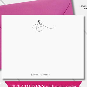 May include: A white flat notecard with a black ampersand design and the name "River Solomon" printed below. A fuchsia envelope and a gold pen are also visible. The text "FREE GOLD PEN with every order" is displayed.