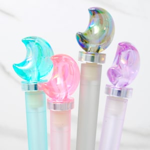May include: Four iridescent moon-shaped bottle stoppers in blue, pink, purple, and green. The stoppers are made of glass and have a silver-colored base.