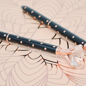 May include: Two black and gold pens with a large clear rhinestone on the end of each pen.