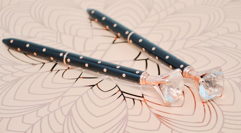May include: Two black and gold pens with a large clear rhinestone on the end of each pen.
