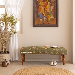 May include: A green and beige patterned bench with turned wooden legs. The bench is in a room with a painting, a plant, and a round jute rug. The text "TirthikaExport" is visible on the bench.