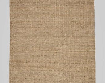 May include: A rectangular, woven jute rug in a natural tan color. The rug has a fringed edge on one side and a simple, textured weave throughout. This rug is suitable for indoor use.