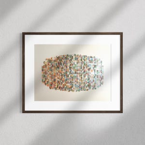 Puede incluir: Impresión artística abstracta enmarcada en un marco de madera marrón oscuro. La obra presenta una composición rectangular de pequeños rectángulos verticales de colores. Los colores incluyen rojo, verde, azul y amarillo, sobre un fondo blanco.