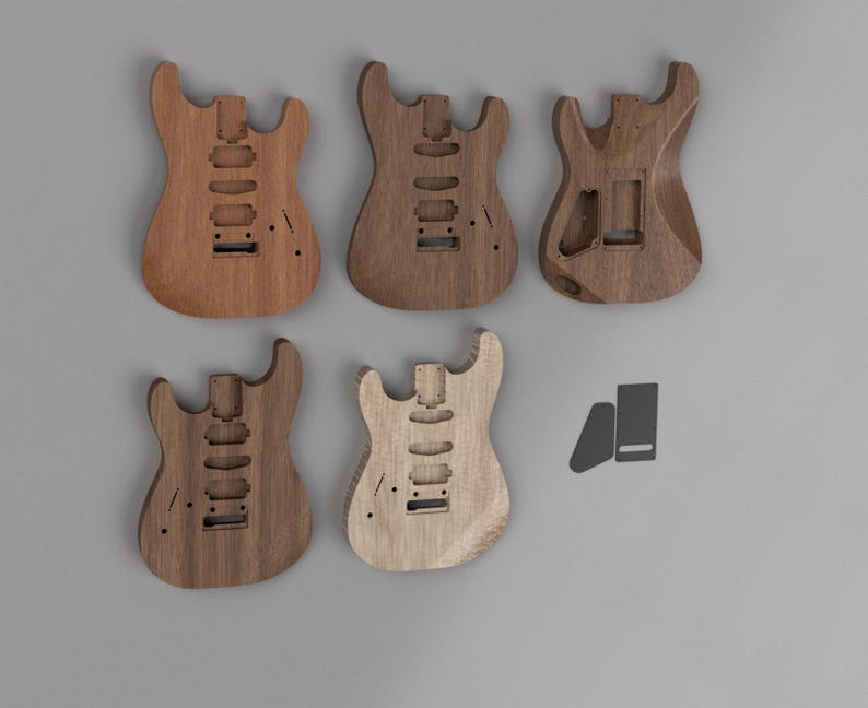 May include: Five unfinished wooden electric guitar bodies with various wood grain patterns and tones. Each body features routed cavities for pickups, a bridge, and a neck pocket. Two small, dark gray rectangular plates are positioned to the right.