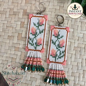May include: A pair of rectangular beaded earrings featuring a white background with a pink floral design, framed by pink beads. Each earring has a fringe of white, pink, and green beads at the bottom and a silver-toned metal ear wire.