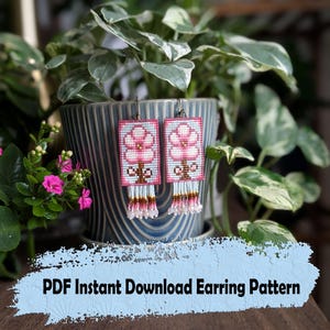Pode incluir: Brincos de contas com um design floral. Os brincos são retangulares com um fundo azul claro e uma flor rosa. A parte inferior dos brincos tem franjas brancas, rosas e marrons. O texto "PDF Instant Download Earring Pattern" está na parte inferior.