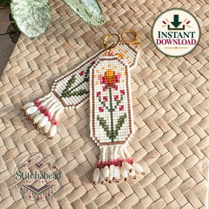 May include: Two rectangular beaded earrings featuring a white background with a central floral design in pink, orange, and green. Each earring has a gold-tone metal hoop at the top and a fringe of white and pink beads at the bottom edge.