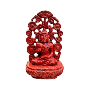 Puede incluir: Una estatua de Buda roja en posición sentada, con intrincados detalles florales y de volutas. La estatua tiene un fondo decorativo y calado. La base también está adornada con patrones florales tallados.