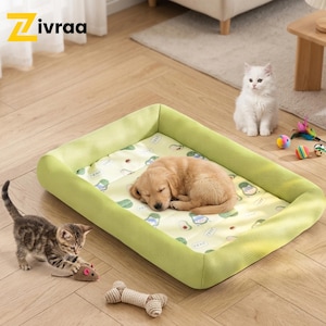 Puede incluir: Una cama verde claro para mascotas con un cachorro golden retriever durmiendo. Un gatito juega con un ratón de juguete cerca. La cama tiene un interior estampado con diseños de aguacate y nubes. Un gatito blanco está sentado en el fondo.