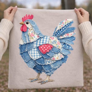May include: A square cushion with a patchwork rooster design. The rooster is made from denim and floral fabrics in blue, red, and white. The cushion has a beige background and embroidered details.