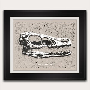 May include: Black and white illustration of a Velociraptor skull. The artwork is set against a speckled tan background and framed in black. The word "VELOCIRAPTOR" is printed in white at the bottom of the image. This piece is suitable for dinosaur enthusiasts.