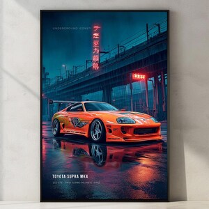 Op de afbeelding: Een ingelijste verticale poster met een feloranje Toyota Supra MK4 sportwagen geparkeerd op een nat asfalt oppervlak in de nacht. De scène bevat een donkerblauwe stedelijke achtergrond met een brug en rode neon Japanse tekst. De tekst luidt TOYOTA SUPRA MK4.