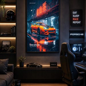 May include: A framed vertical wall poster featuring a bright orange Toyota Supra MK4 parked on a wet city street at night under glowing red neon signs. The text on the poster reads TOKYO DIVISION, TOYOTA SUPRA MK4, and 2JZ-GTE TWIN TURBO ENGINE.