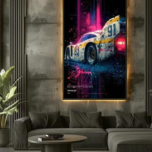 May include: A framed wall art print featuring a weathered Porsche 962 race car with the number 91, set against a dark background with vibrant pink and blue neon light streaks. The text reads MOTORSPORT LEGENDS, PORSCHE 962, and 1989.