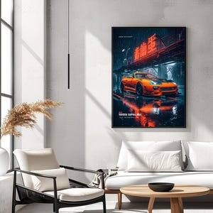 May include: A framed wall art print featuring an orange Toyota Supra MK4 parked on a wet city street at night. The scene includes neon red Japanese text above the car, rain-slicked pavement with reflections, and the text TOYOTA SUPRA MK4 below.