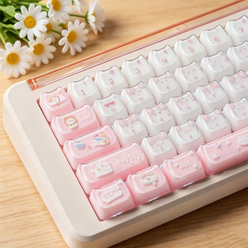Puede incluir: Un teclado mec&aacute;nico con marco blanco y teclas personalizadas con dise&ntilde;o de gatos. Las teclas combinan blanco y rosa suave, decoradas con peque&ntilde;as ilustraciones de gatos, cupcakes y etiquetas de texto como shift, alt y ctrl.