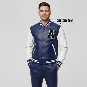 May include: A navy blue and white varsity jacket with the letter "A" on the chest. The jacket has white sleeves, a navy blue body, and striped cuffs and waistband. The jacket is part of a matching set.