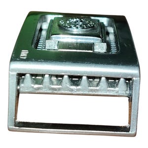 K&ouml;nnte beinhalten: Silberfarbene Metallschnalle mit rechteckiger Form. Die Schnalle hat ein zentrales dekoratives Element und das Wort "ITALY" ist sichtbar. Die Schnalle hat ein strukturiertes Design und einen Dornverschluss.