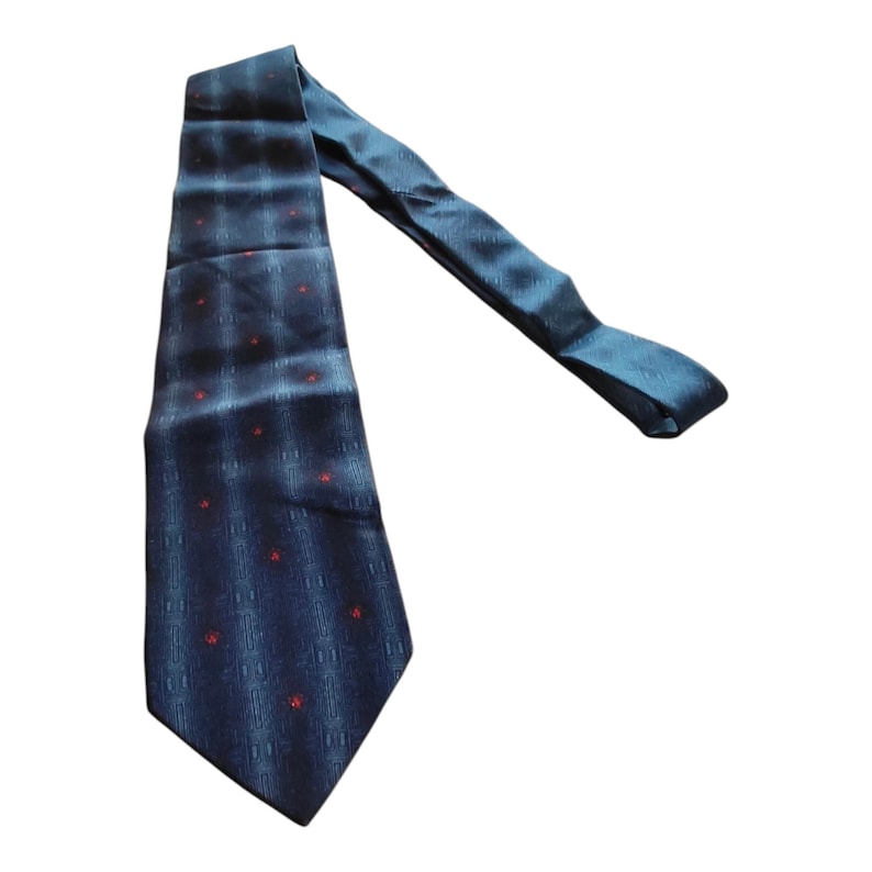 Peut inclure: Une cravate bleu marine avec un motif quadrill&eacute; subtil et de petits points rouges. La cravate est faite d'une mati&egrave;re lisse, peut-&ecirc;tre de la soie, et convient aux tenues formelles ou professionnelles.