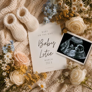 May include: A pair of cream-colored knit baby booties next to a white announcement card that reads BABY ON THE WAY Baby Lotie MARCH 202 X, accompanied by a black and white ultrasound scan and a floral arrangement of white roses and blue flowers.